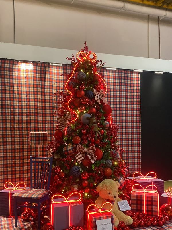 Árvore em vermelho e xadrez com presentes iluminados e urso na base