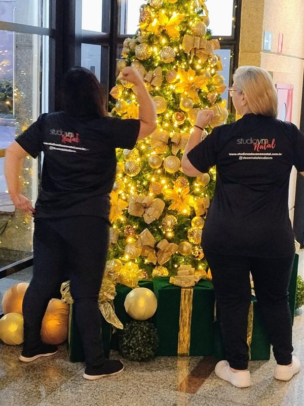 Equipe do Studio VM Natal montando uma árvore dourada no lobby de um edifício