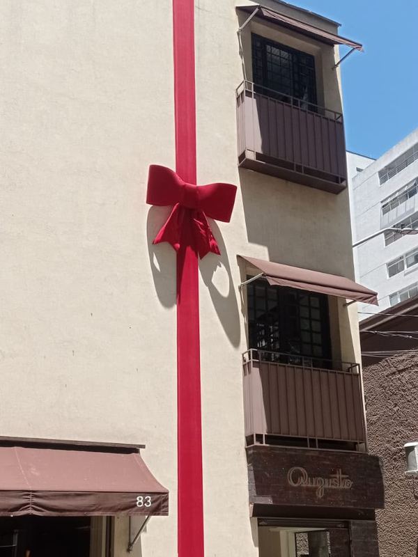 Fita e laço vermelho embalando a fachada de um edifício comercial