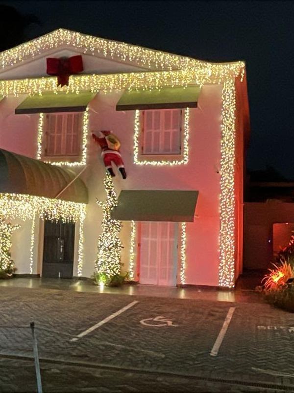 Fachada comercial iluminada com Papai Noel escalando a parede