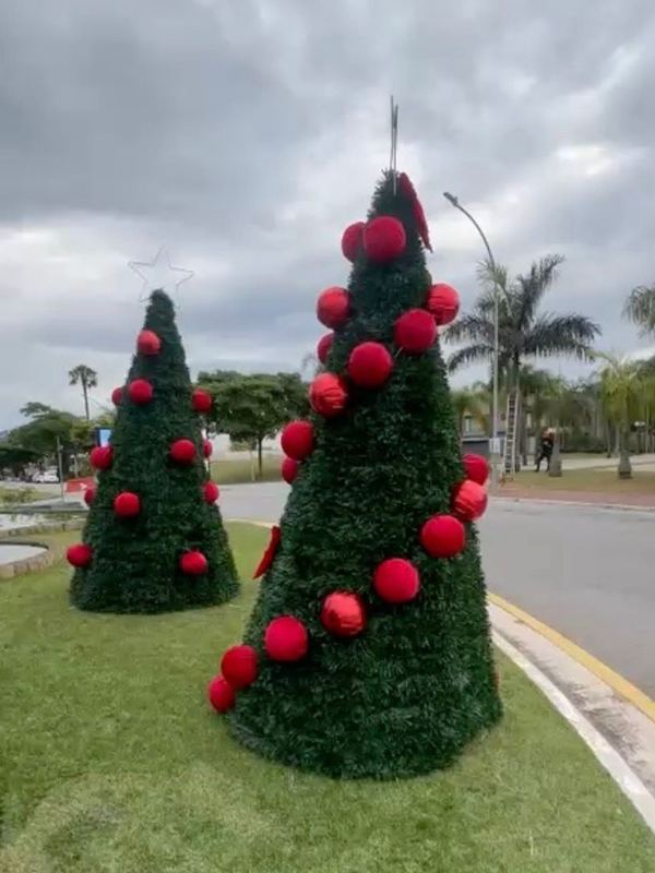 Cones de Natal em vermelho no jardim de acesso a um condomínio