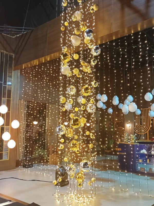 Cenografia de Natal com cortina de luzes e esferas suspensas