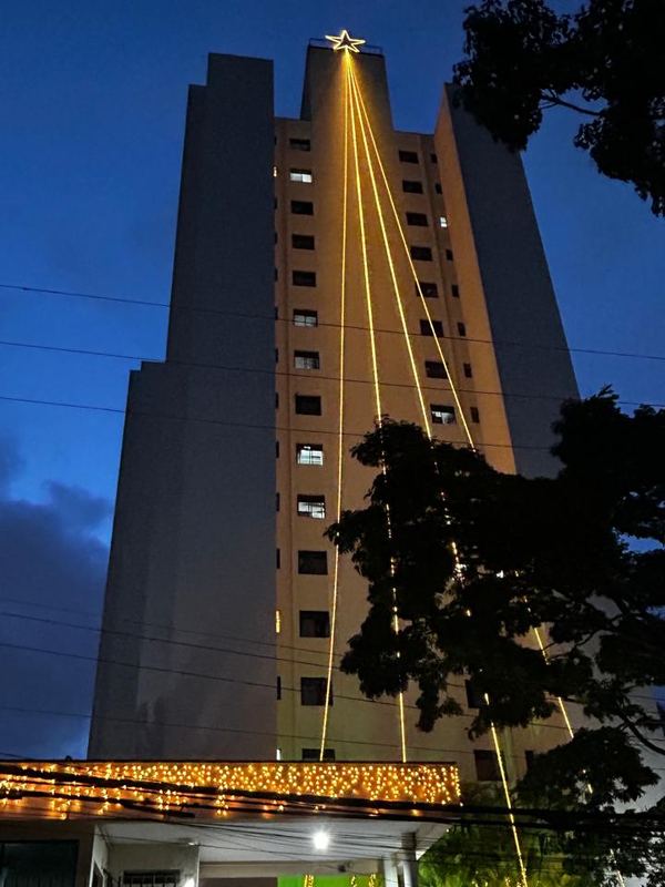 Estrela no topo de um prédio residencial com cascatas de luz até a portaria