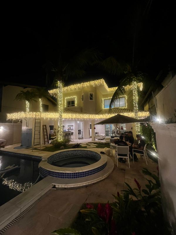 Casa com cascatas de luz no beiral e área de piscina iluminada
