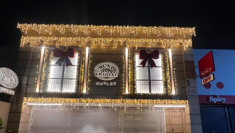 Fachada de loja iluminada com cascatas de luz e laços nas vitrines